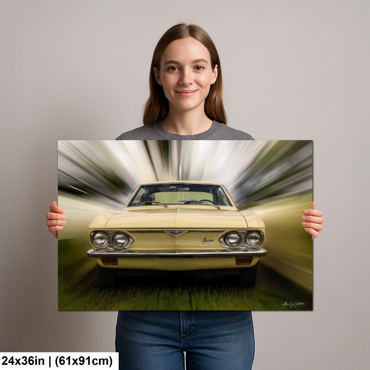 A woman is holding up a framed print of a yellow car with a blurred background, creating a sense of motion.