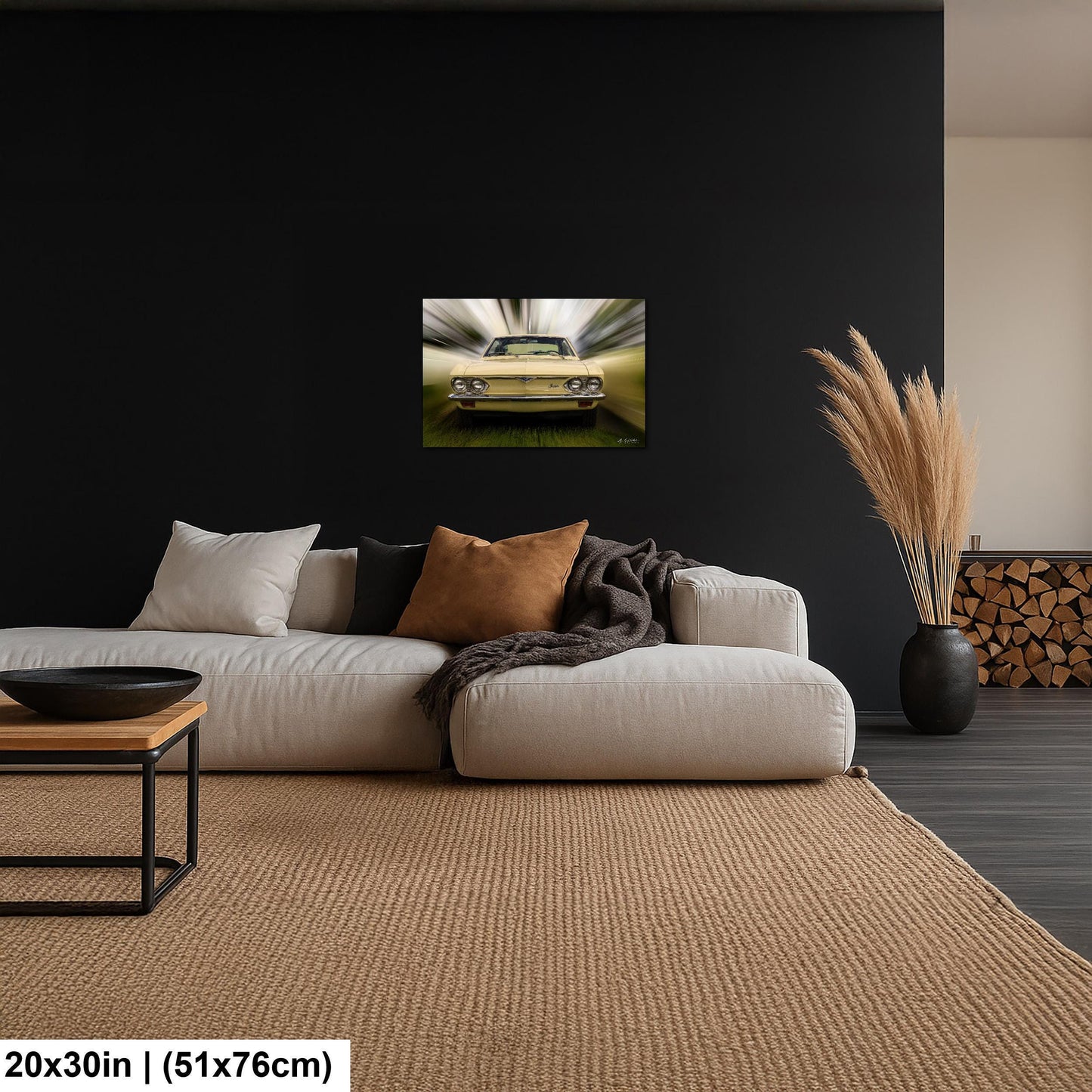 a living room with a large, plush white sofa and a wooden coffee table. Above the sofa, there is a framed picture of a yellow car, and a vase with dried flowers is placed on the floor next to the sofa. The walls of the room are painted black, and there is a rug on the floor.